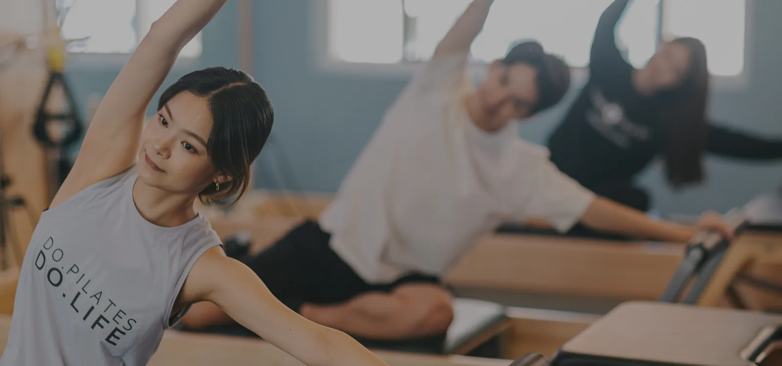 Pilates class with instructor and participants exercising on reformers in studio