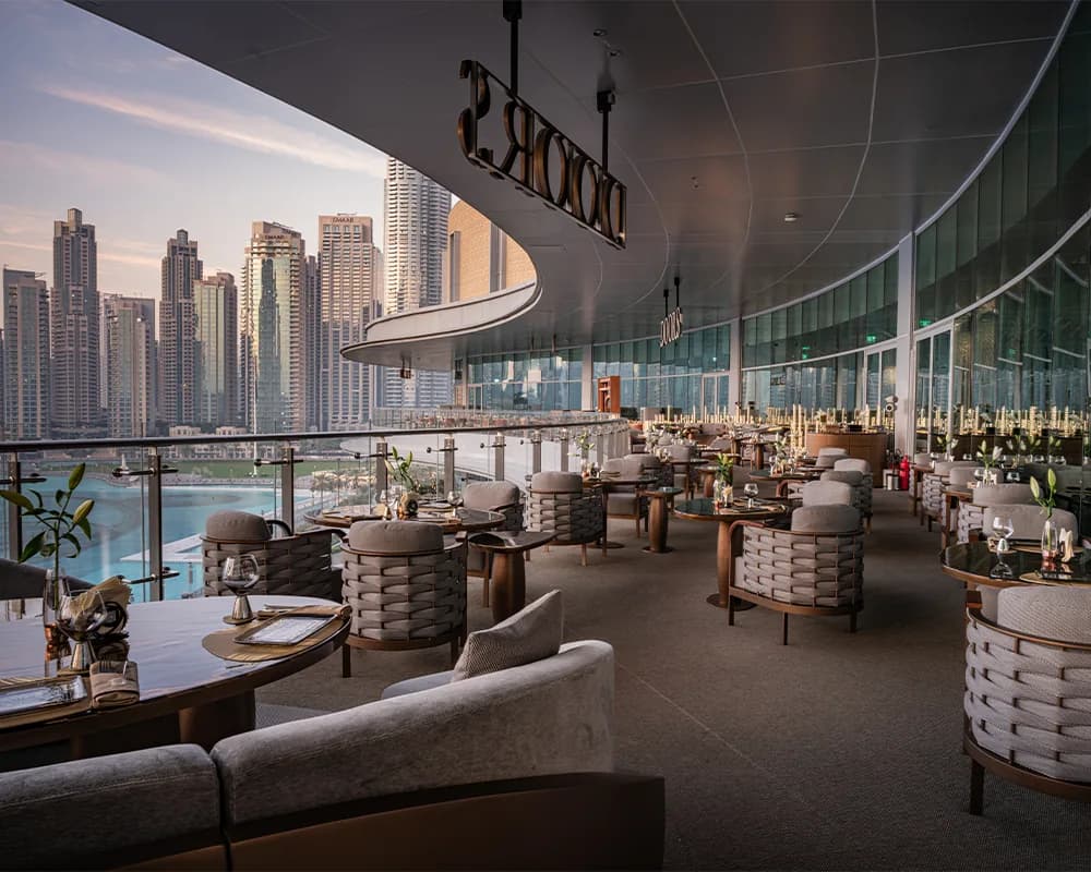 Upscale restaurant dining room with waterfront views of high-rise buildings and marina.