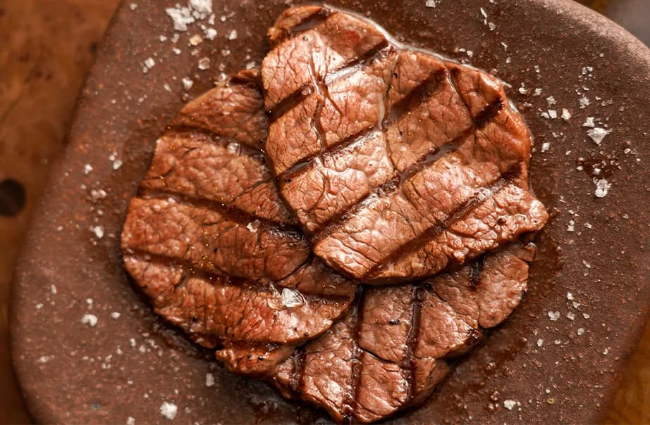 Seared steak with crust and sea salt on dark plate