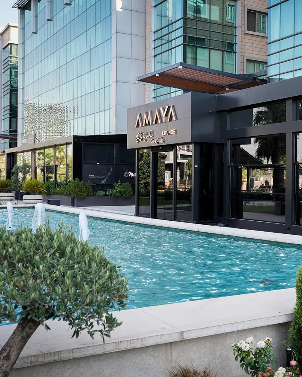 Amaya Best Shisha lounge storefront with black exterior beside a pool and landscaped courtyard