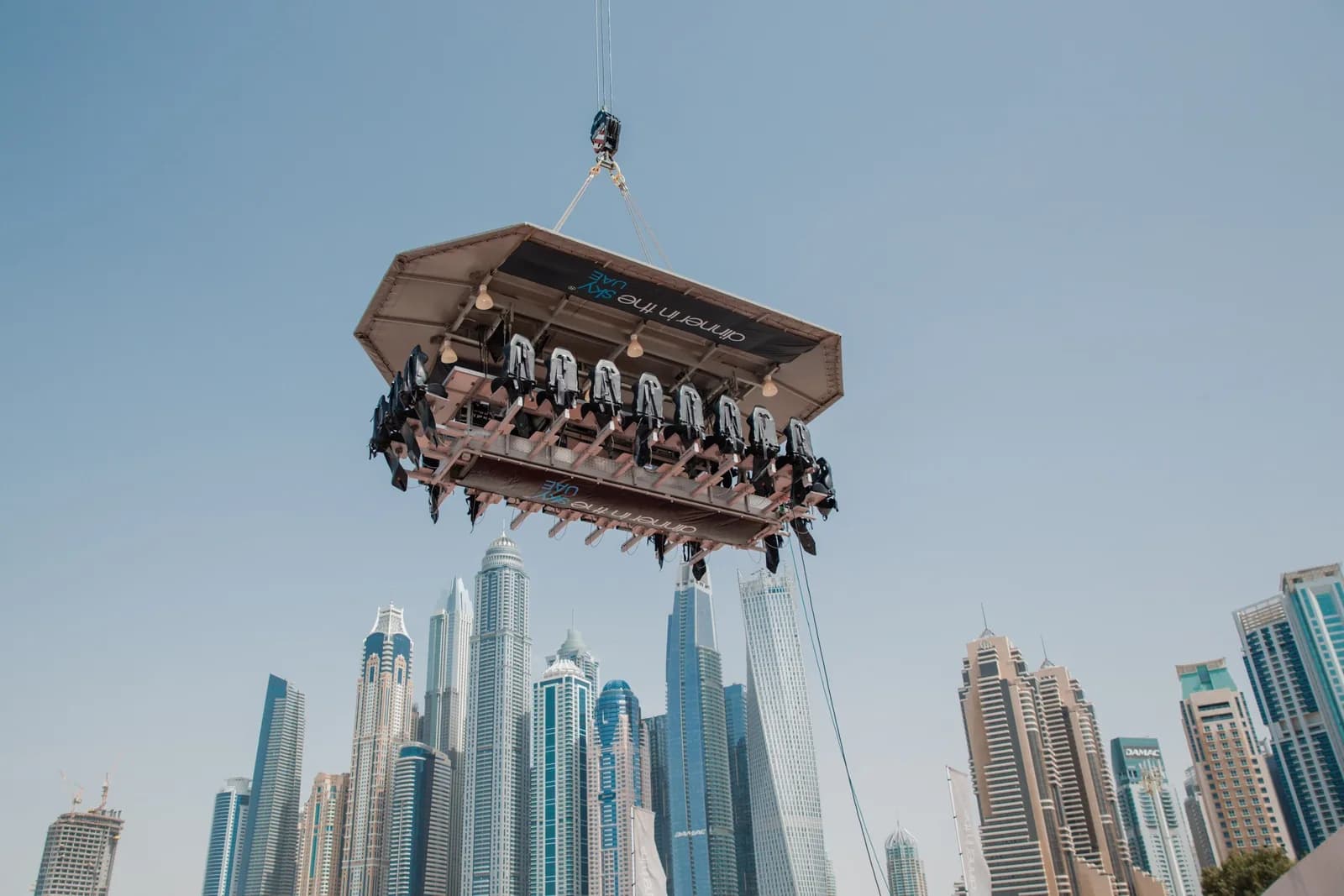 Suspended dining platform with seated guests hovering above a city skyline