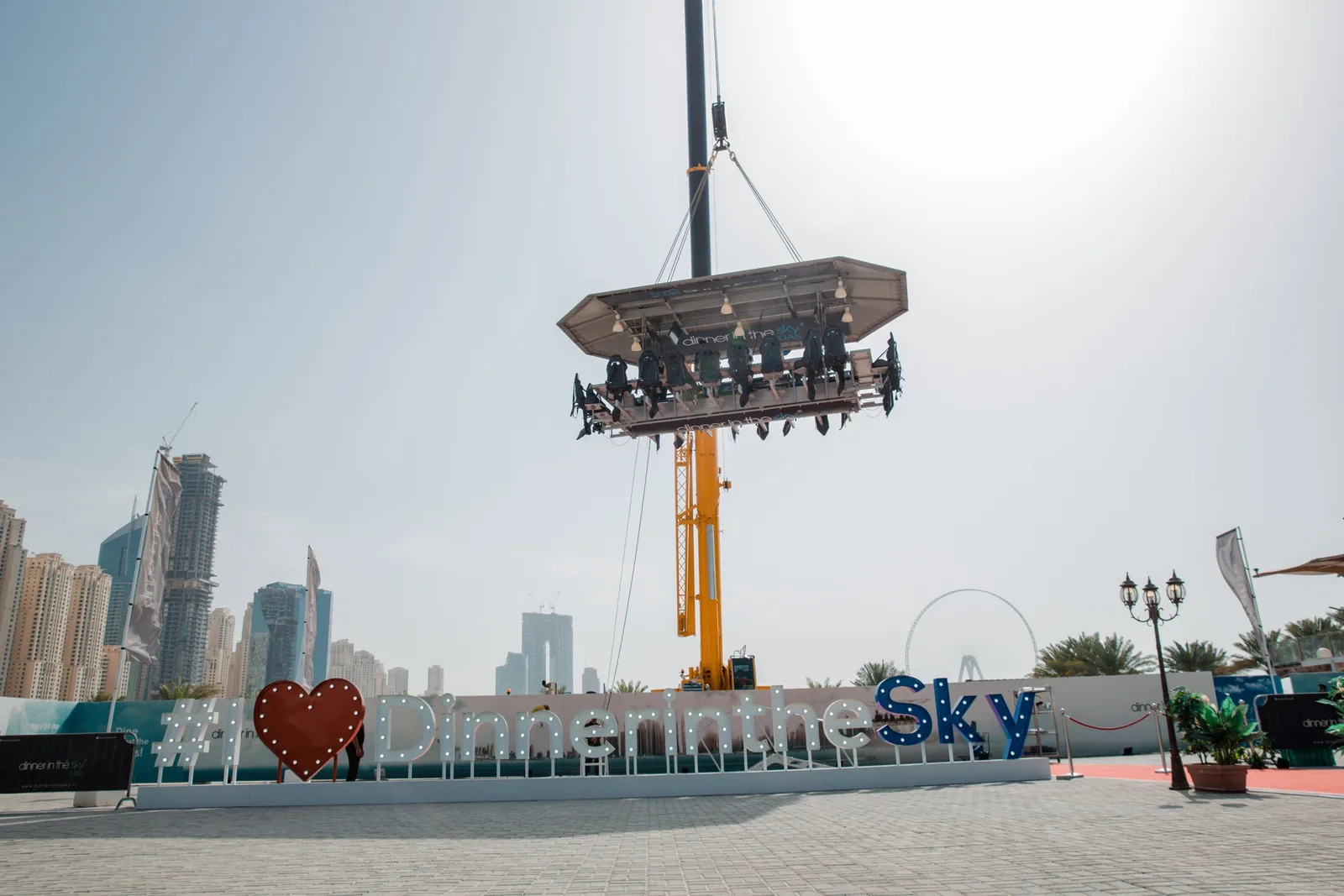 Suspended dining platform elevated above waterfront with Dubai skyline and palm trees behind