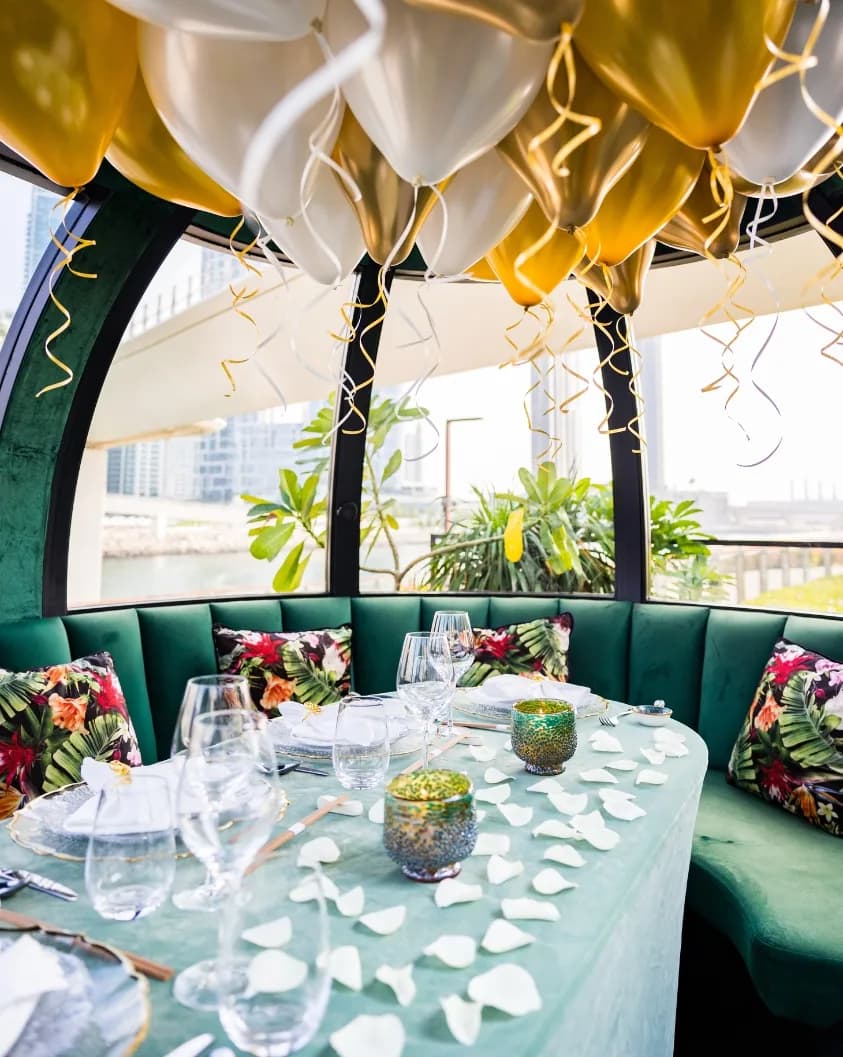 Upscale restaurant private dining pod with green seating, festive balloons, and formal table setting