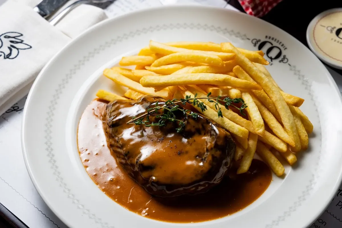 Steak with herb garnish and fries on white restaurant plate