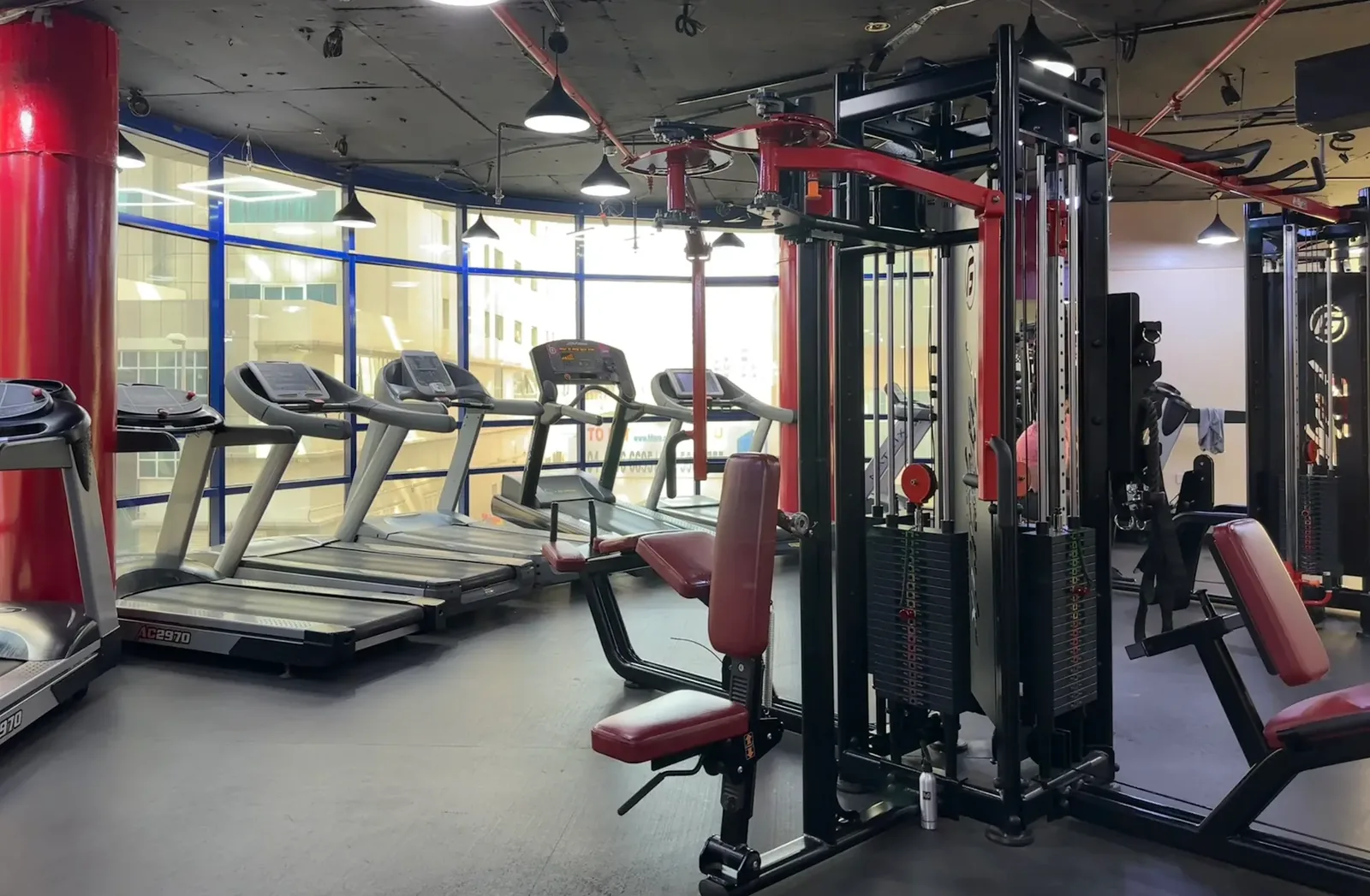 Gym interior with treadmills and weight training equipment under industrial lighting