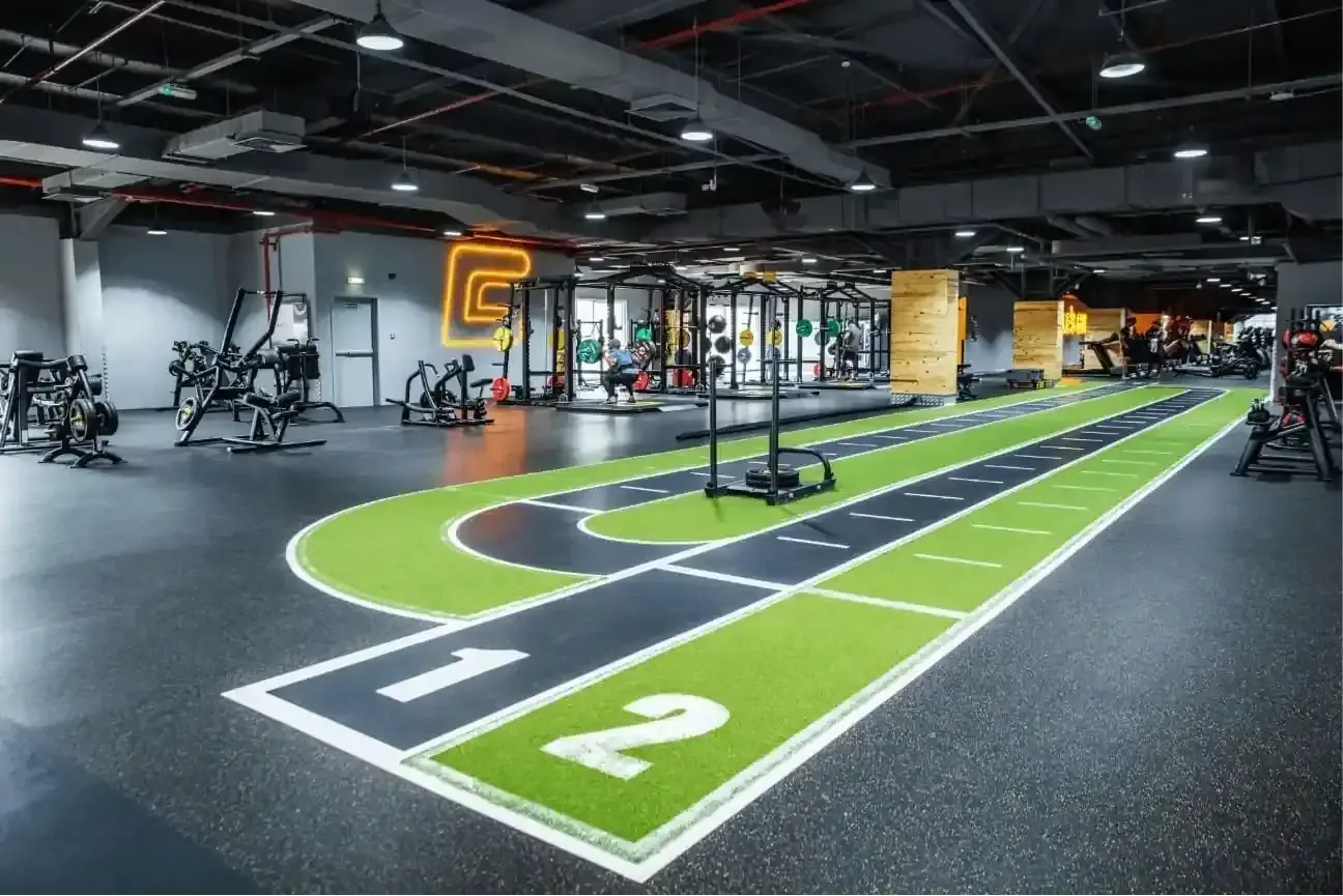 Modern gym interior with numbered lanes, exercise equipment, and industrial ceiling lighting