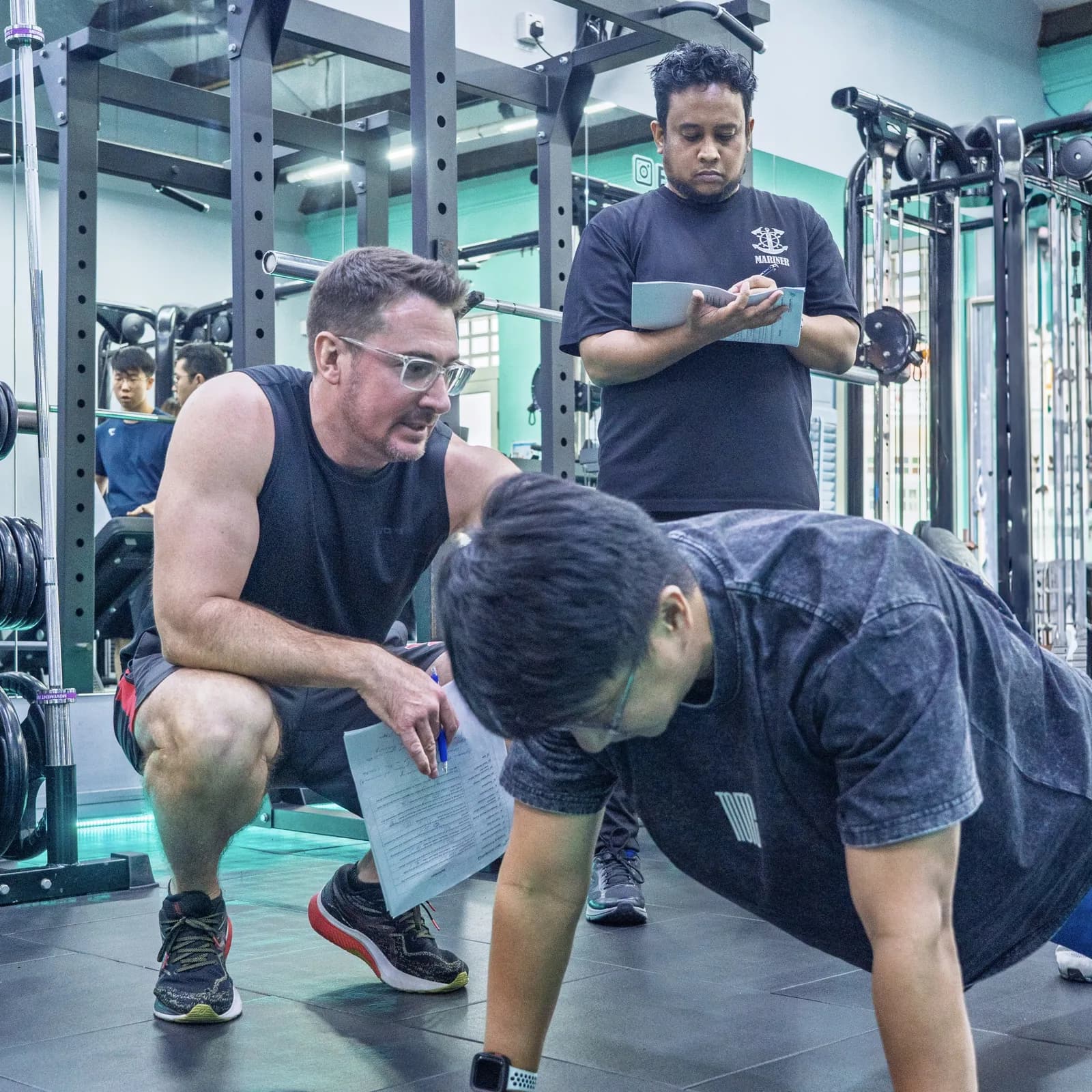 Personal trainer instructing client on exercise form in gym with equipment visible
