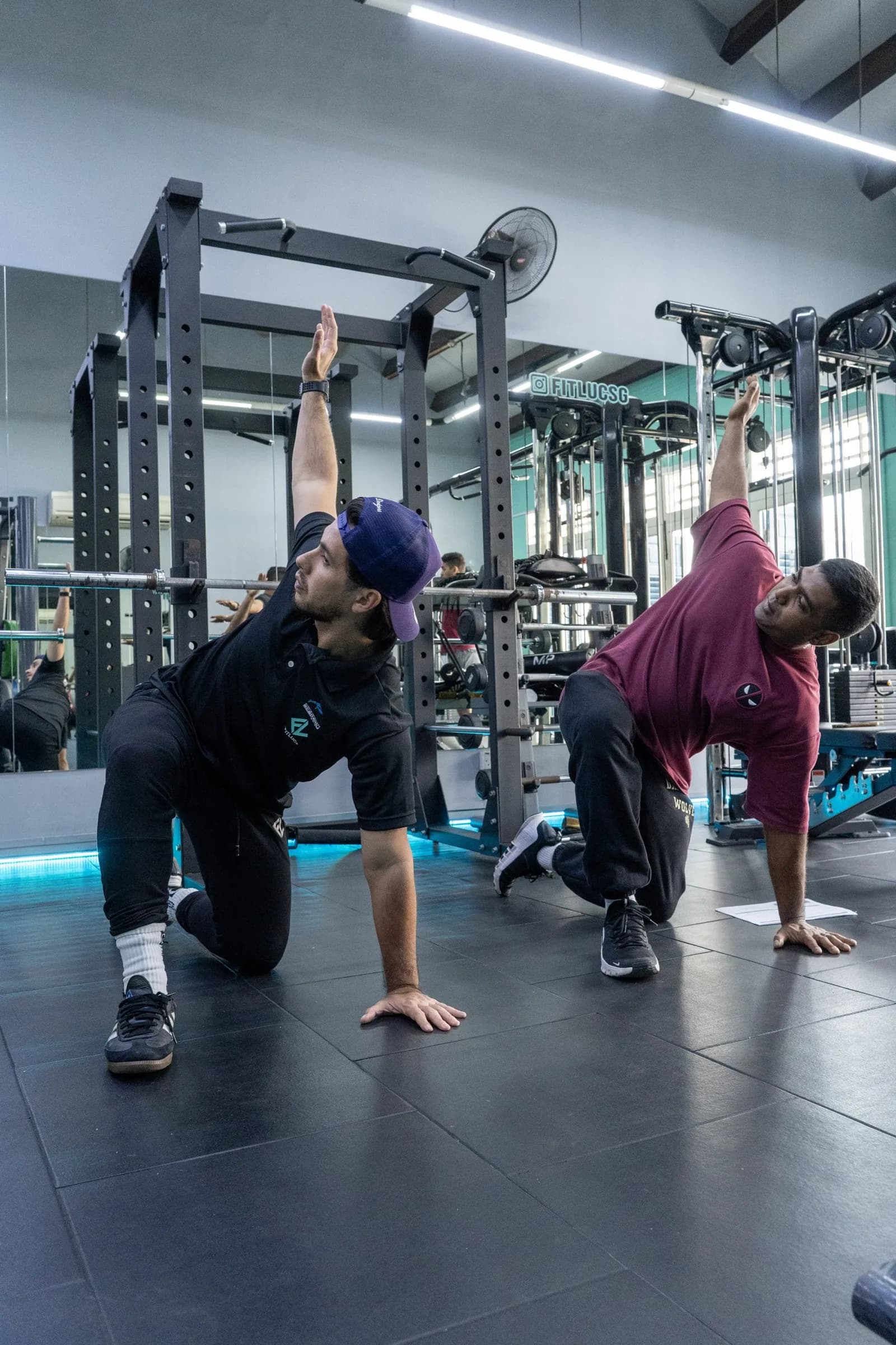 Personal trainers demonstrating pull-up bar exercises in a gym with modern equipment
