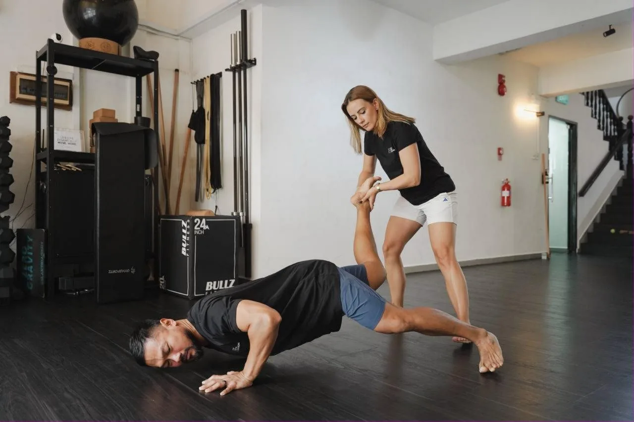 Personal trainer instructing client in plank position at fitness studio