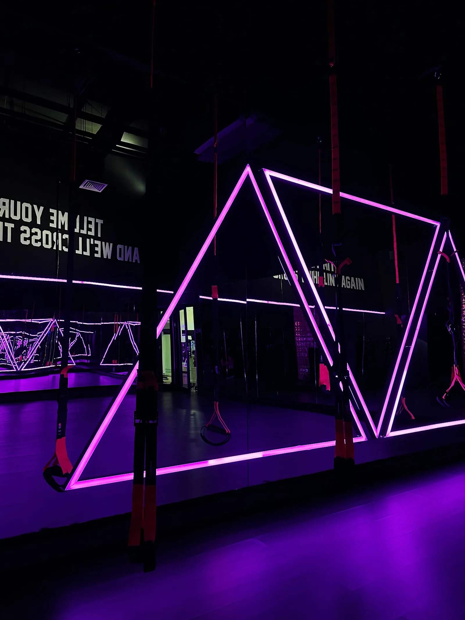 Studio interior with neon pink geometric frames and purple lighting at RESHAPE fitness studio