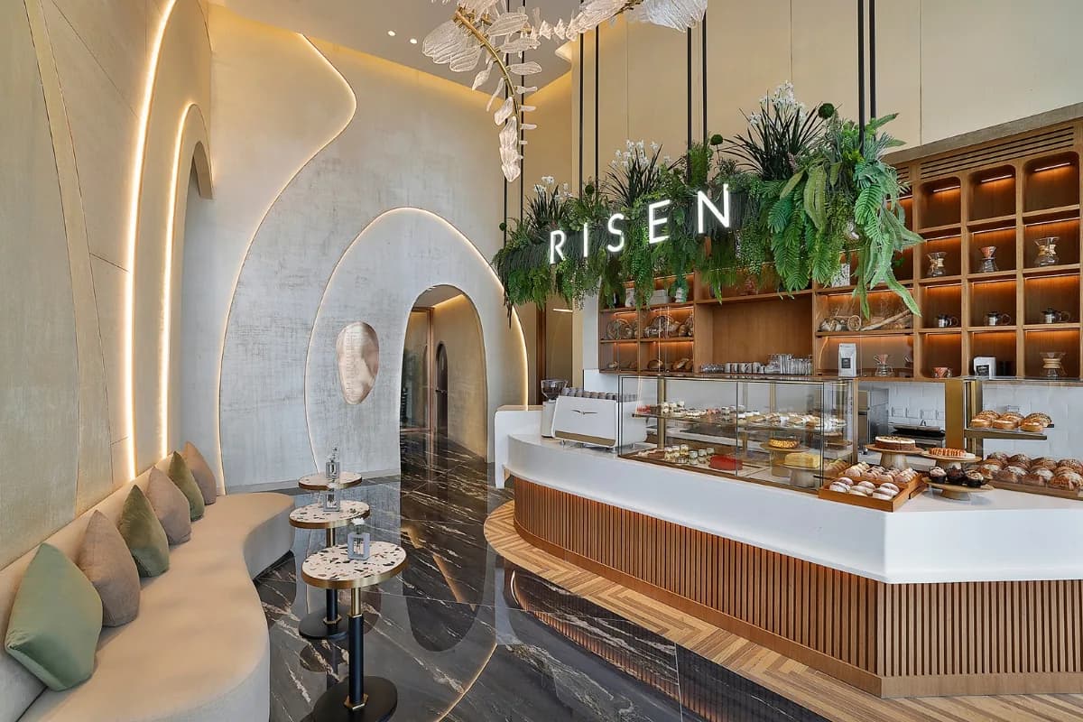 Risen Café interior with curved architectural features, neon accents, and pastry display counter
