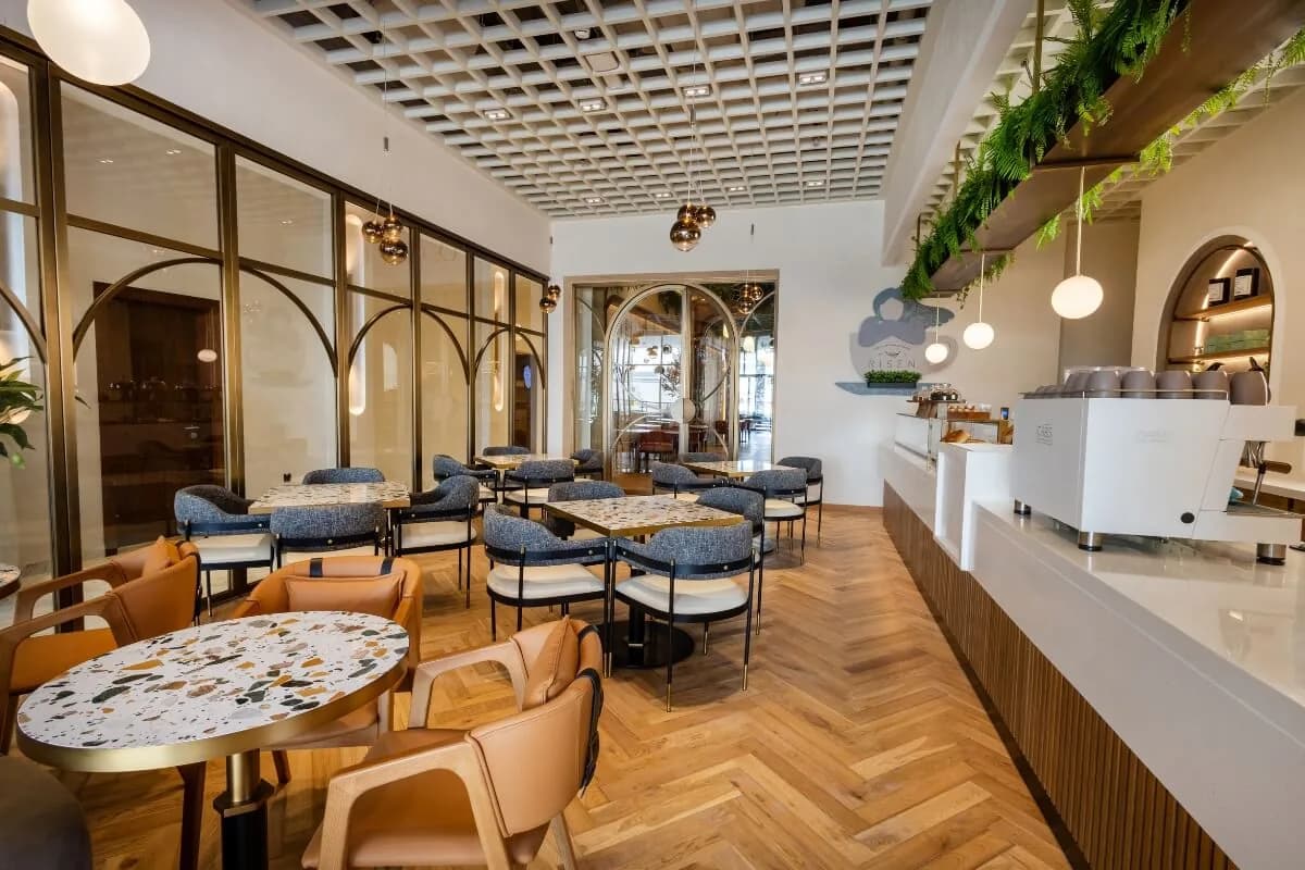 Modern café interior with blue and orange seating, geometric ceiling details, and a service counter