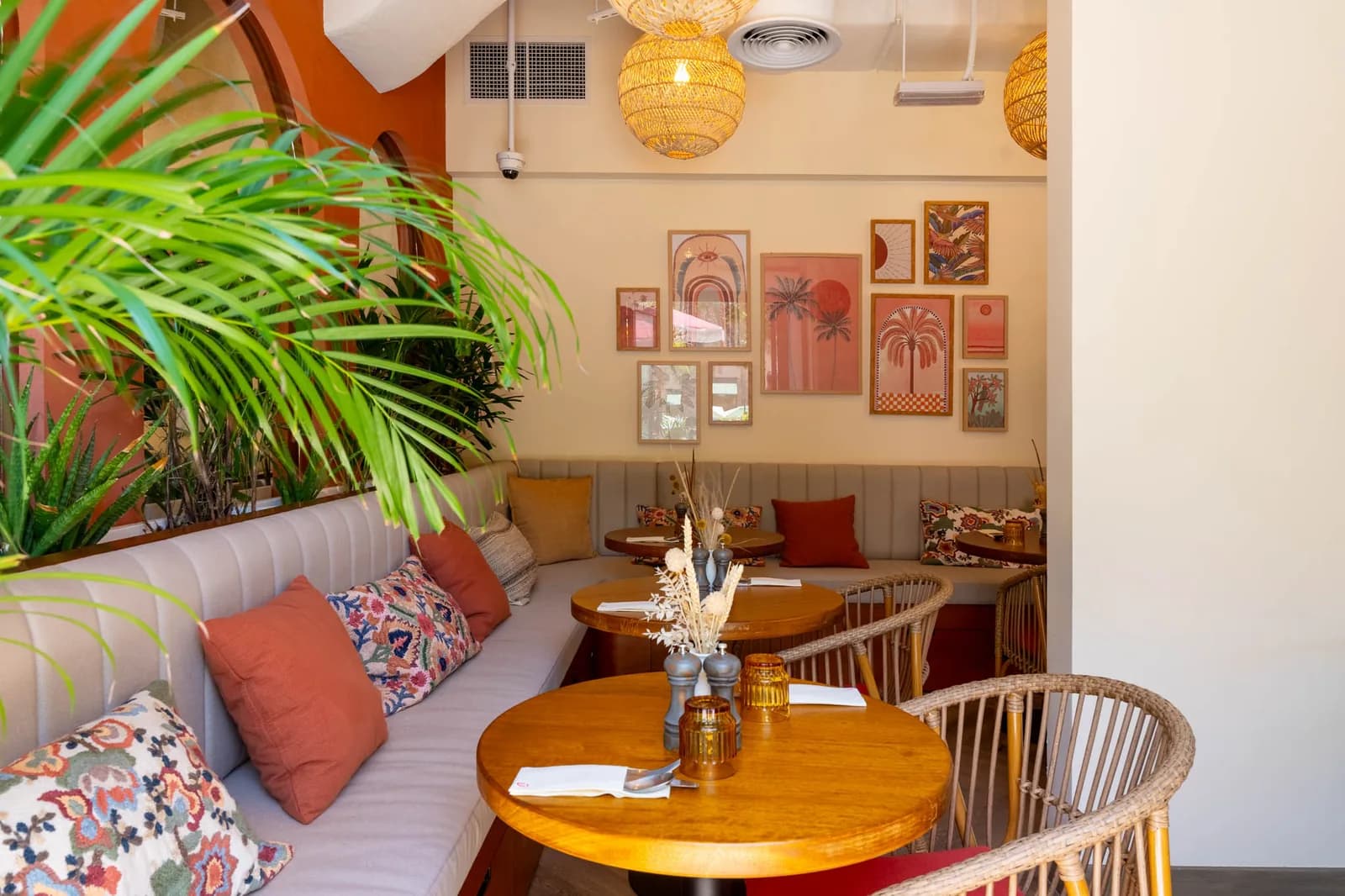 Warm café interior with orange accents, pendant lighting, wooden furniture, and plant décor