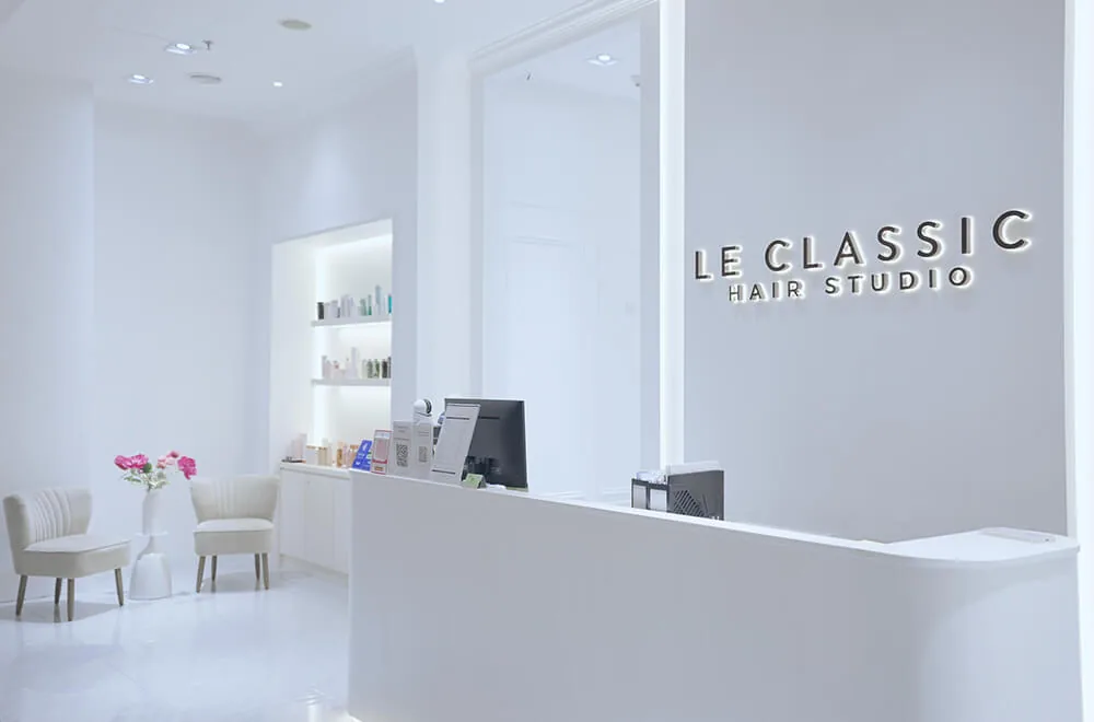 Le Classic Hair Studio reception area with white interior, modern desk, and product shelving