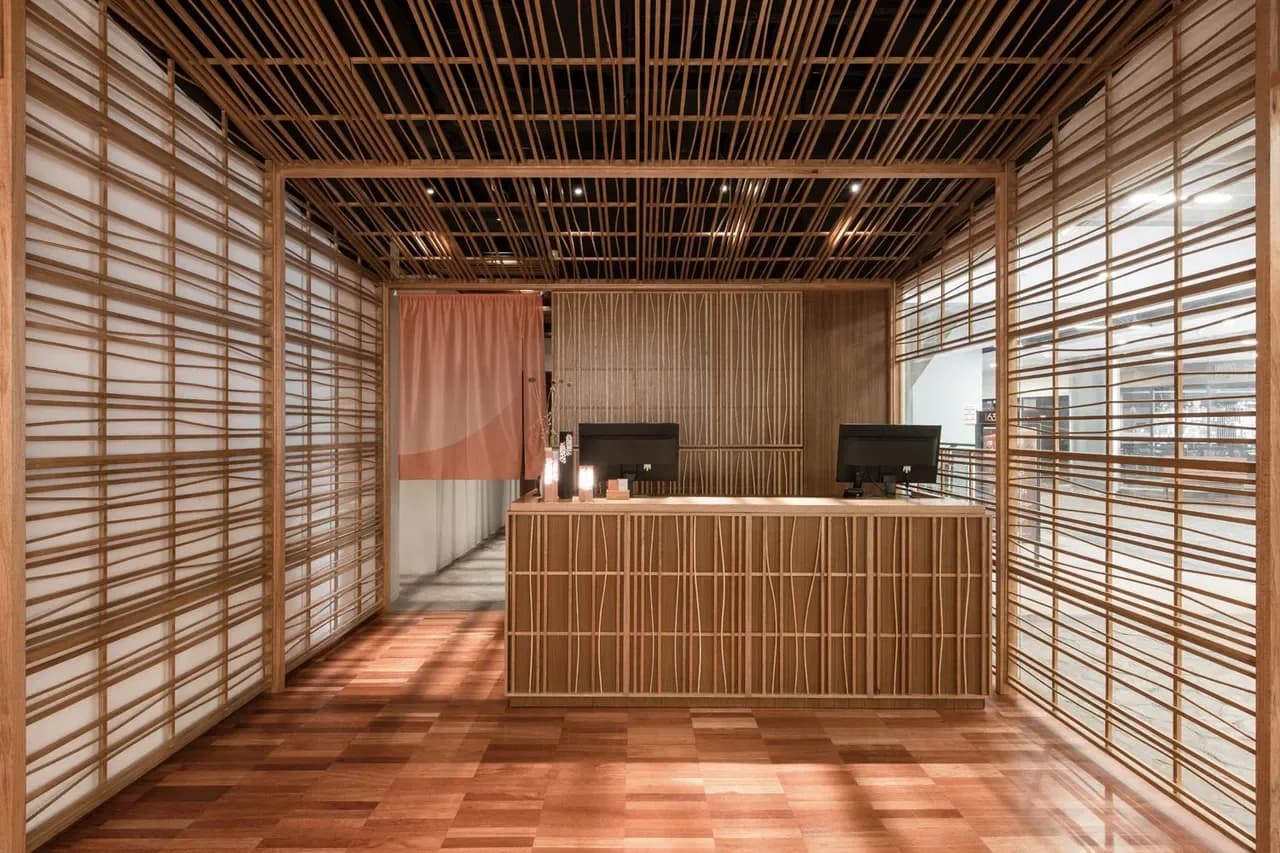 Modern spa reception with wooden lattice screens, reception desk, and warm lighting