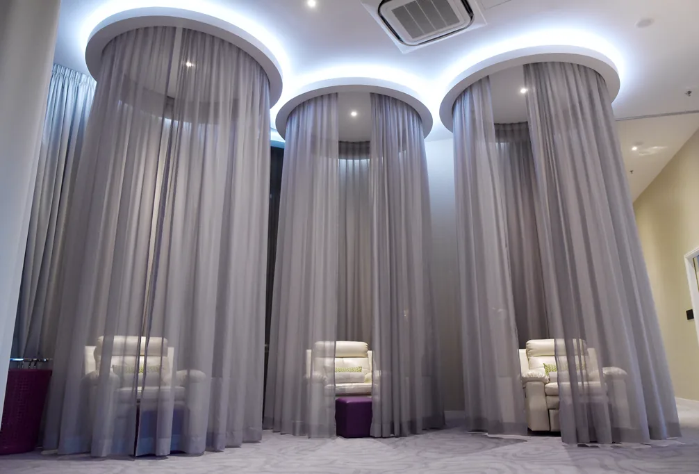 Modern spa interior with three private treatment pods separated by grey curtains and ambient lighting