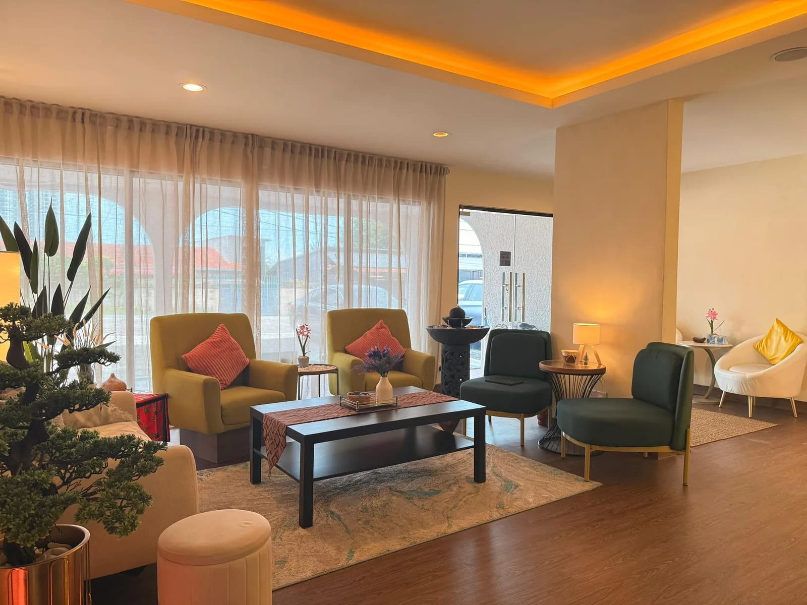 Modern spa lounge with gold armchairs, black coffee table, indoor plants, and warm ceiling lighting.