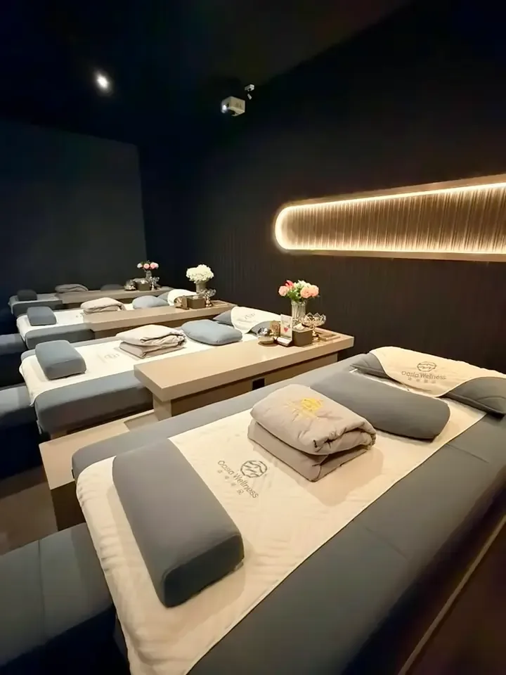 Spa treatment room with multiple massage beds, linens, and ambient lighting