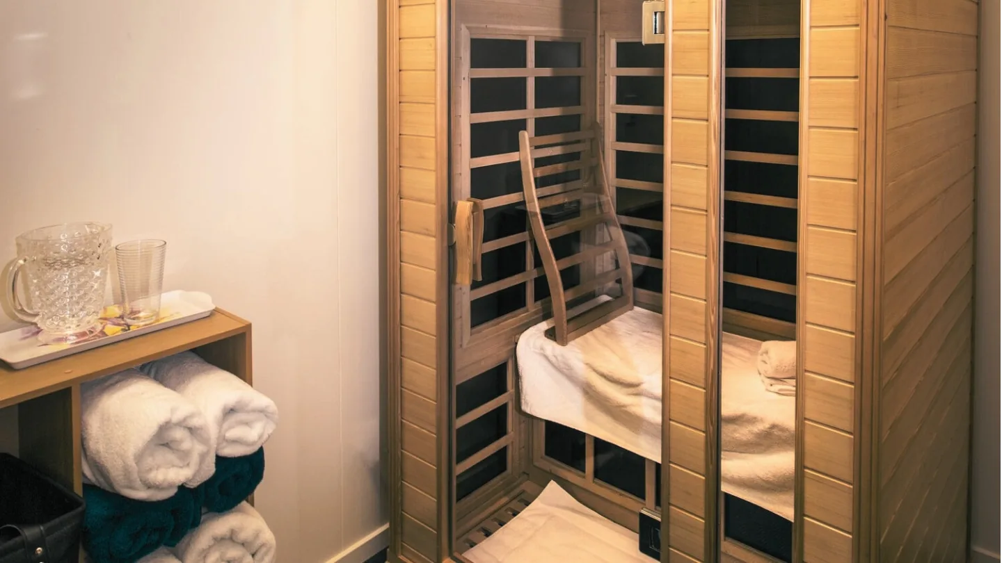 Infrared sauna room with wooden doors, benches, and white towels