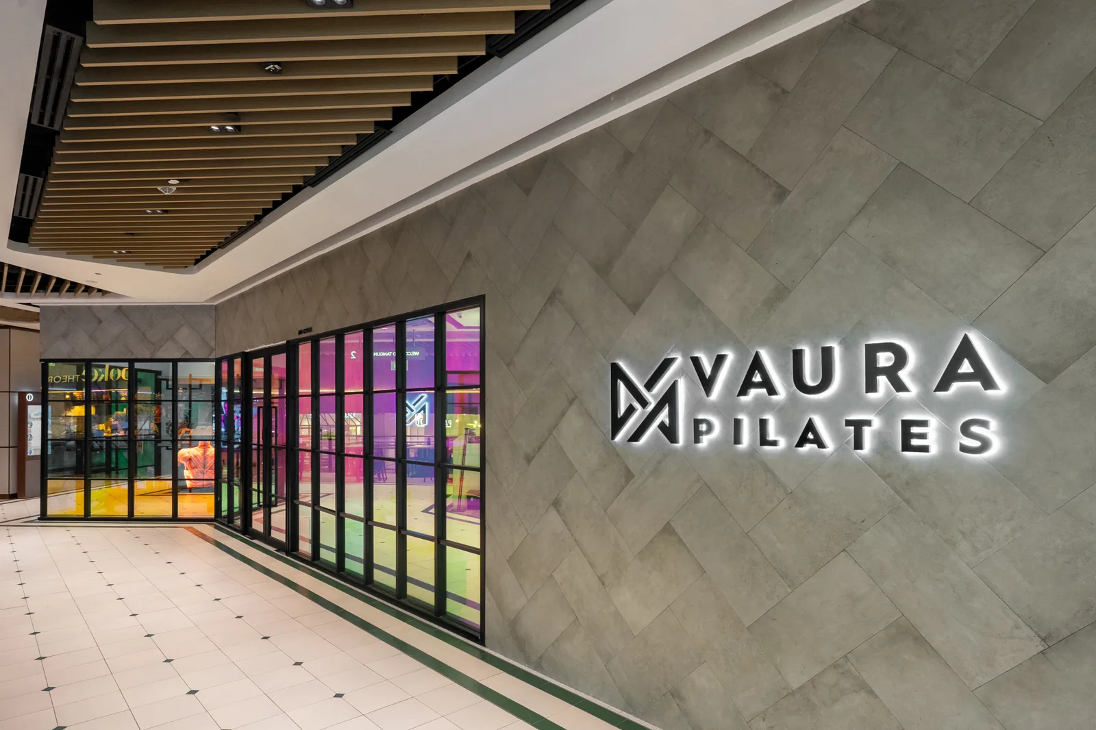 VAURA Pilates storefront with illuminated logo and glass entrance doors in mall corridor