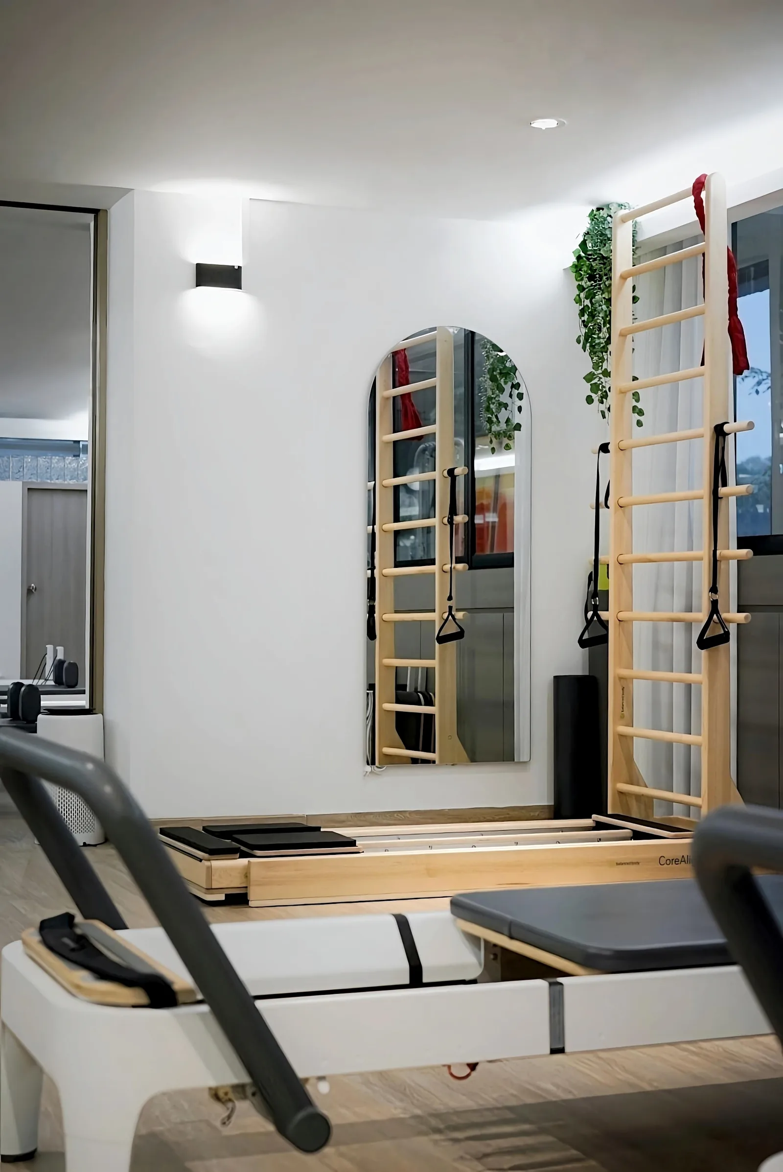 Modern pilates studio with wooden ladder bars, suspension training equipment, and reformer bed