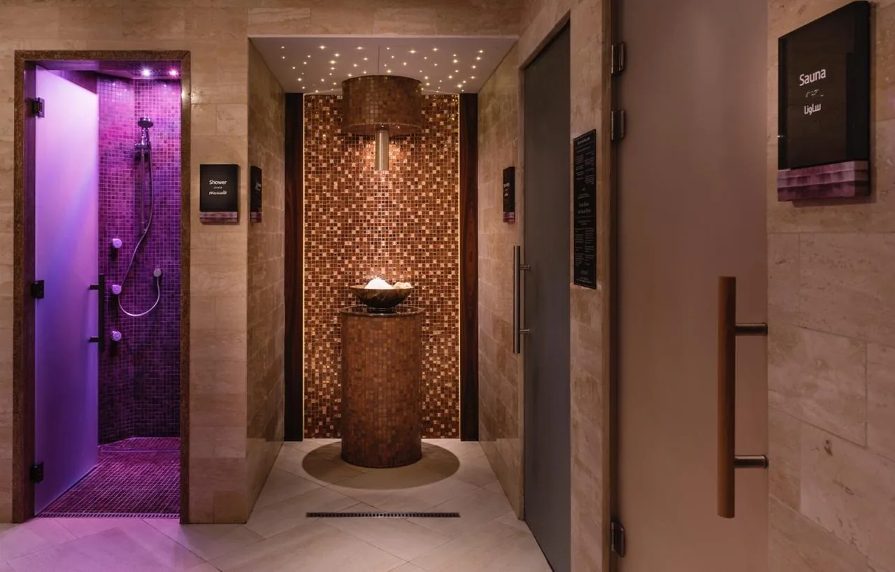 Spa hallway with purple-lit shower room, brown mosaic feature, and treatment room doors