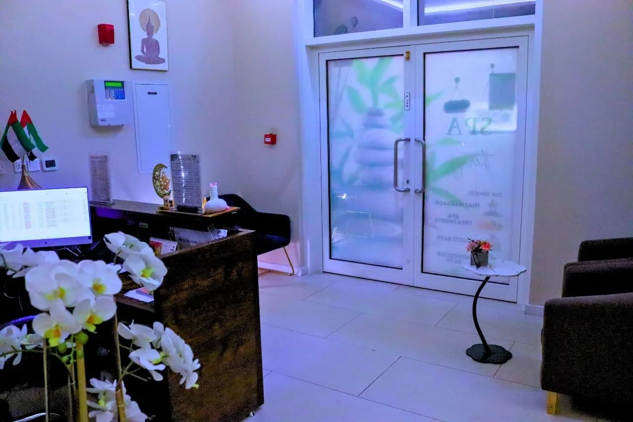 Modern spa reception area with black desk, white orchids, glass doors, and contemporary furnishings
