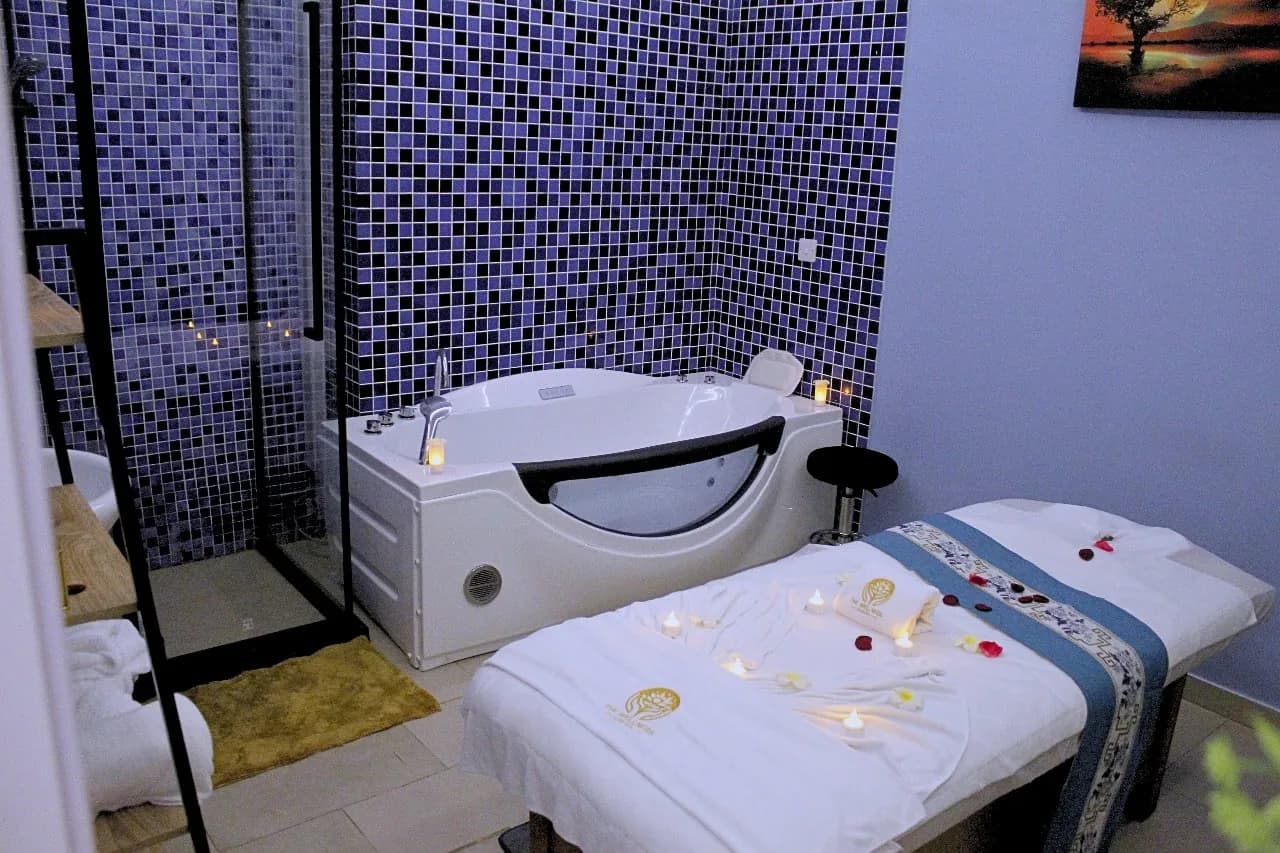 Spa treatment room with tub, massage bed, and decorative flowers