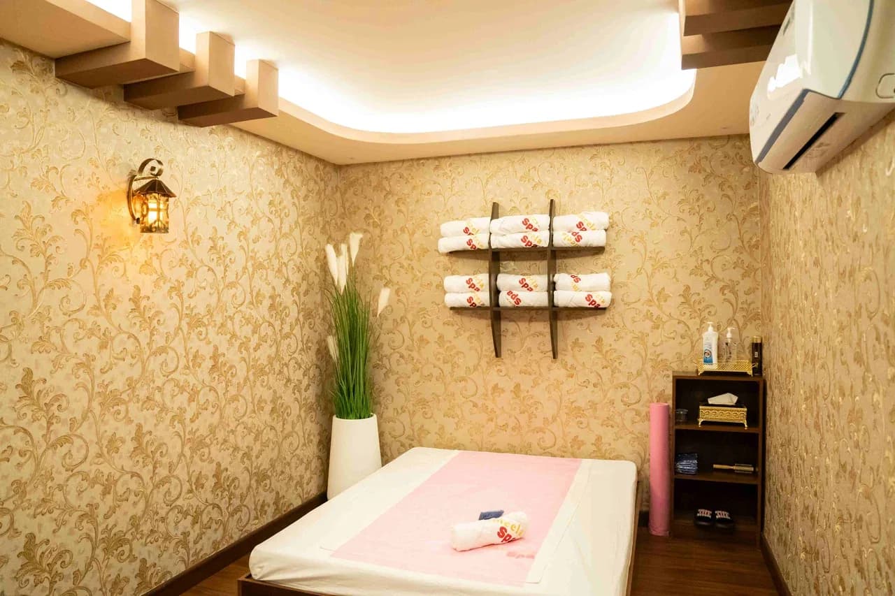 Spa treatment room with massage bed, towel storage, and relaxation decor