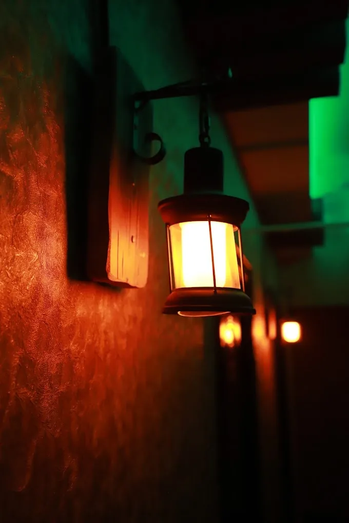 Glowing lantern on textured red wall with warm lighting at spa entrance