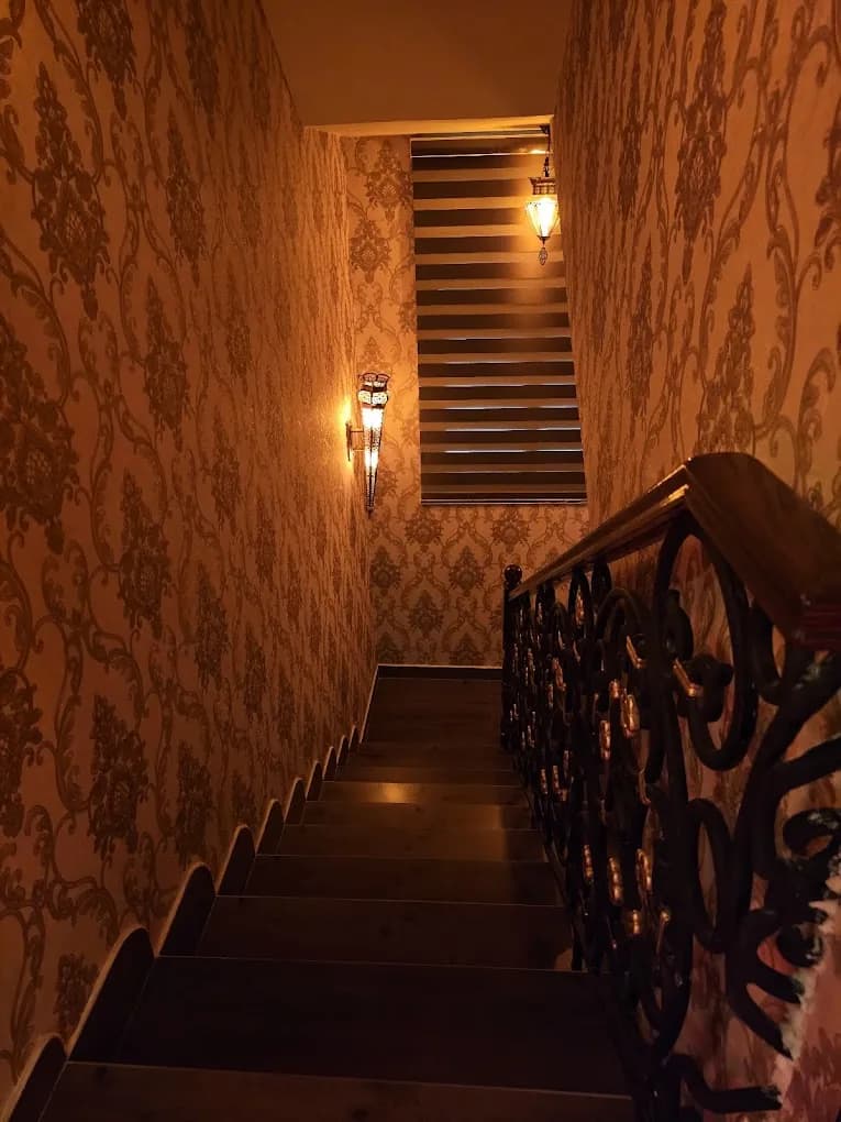 Warm-lit stairwell with damask wallpaper and decorative sconces leading to spa entrance