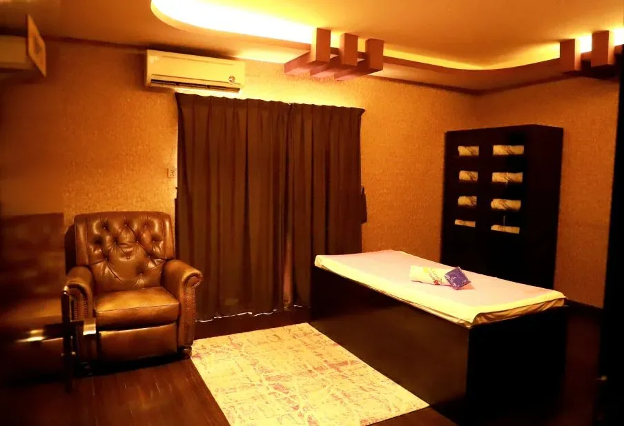 Spa treatment room with massage bed, leather chair, and warm lighting