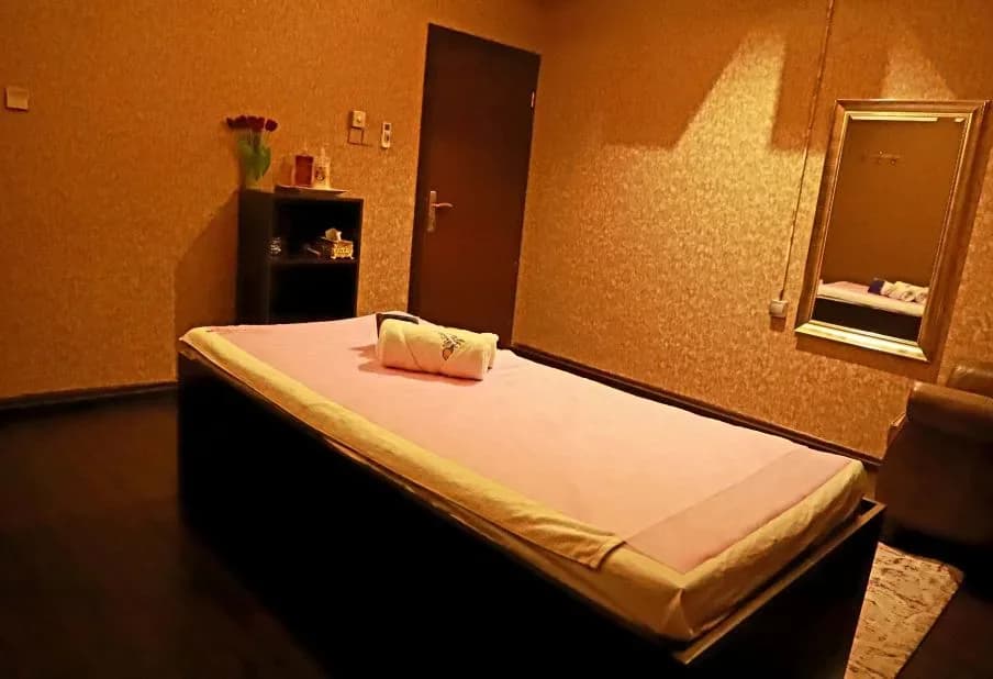 Massage treatment room with padded table, folded towels, and warm ambient lighting