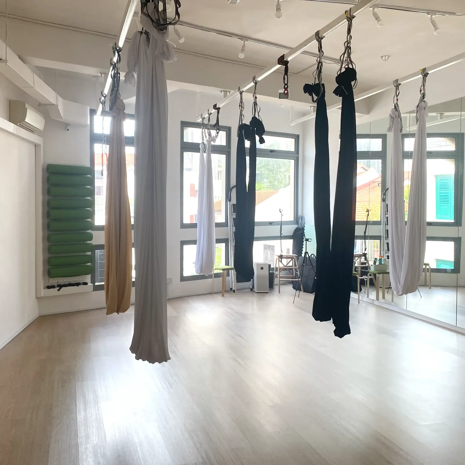 Aerial yoga studio with suspended hammocks in black, white, and gray from ceiling beams