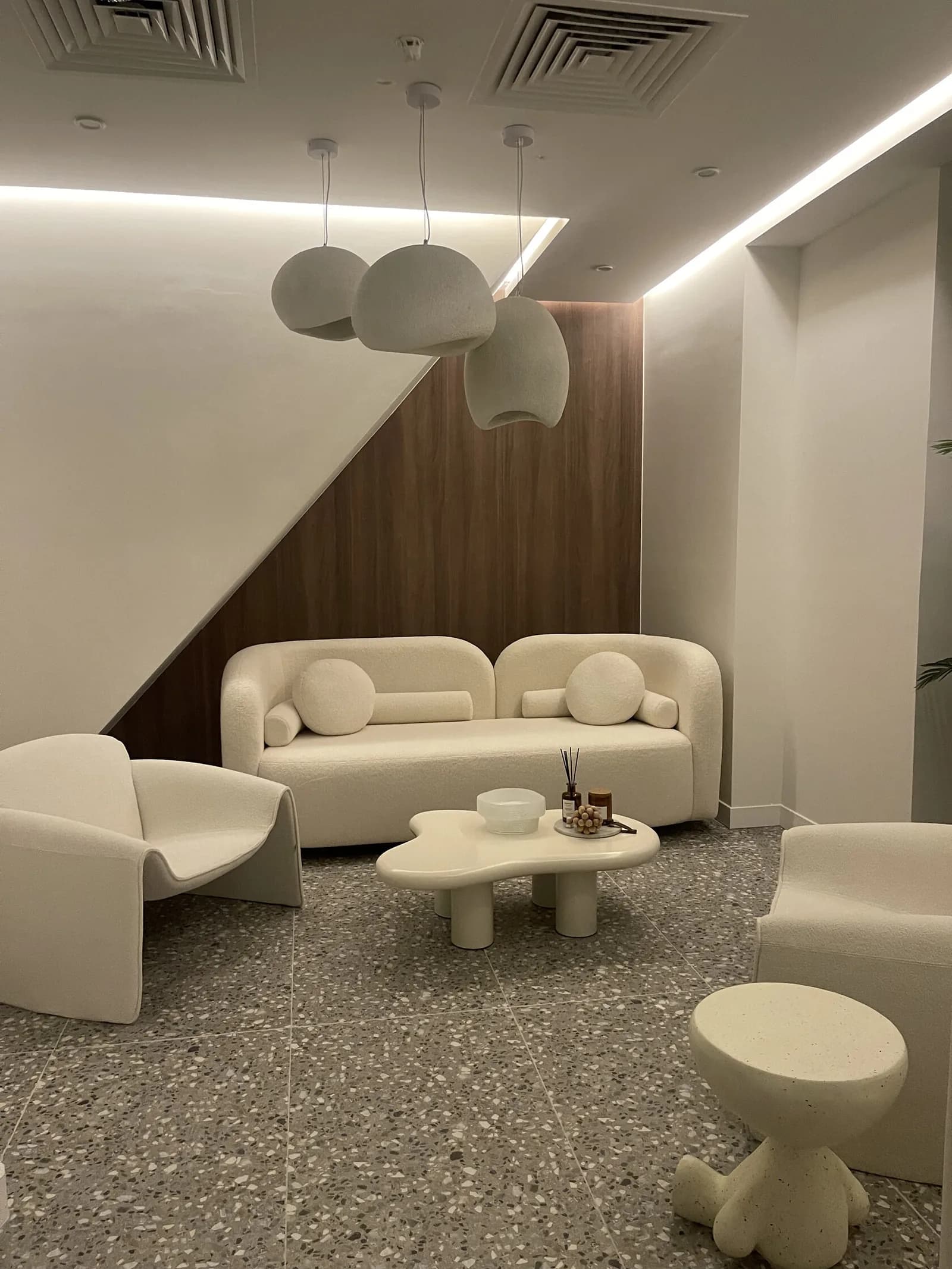 Modern salon lounge with cream sofa, pendant lights, and contemporary furniture