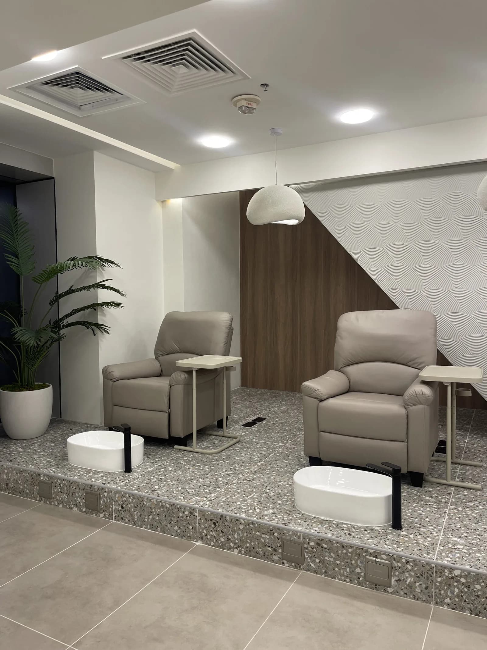 Modern salon waiting area with grey recliners, pendant light, and contemporary decor