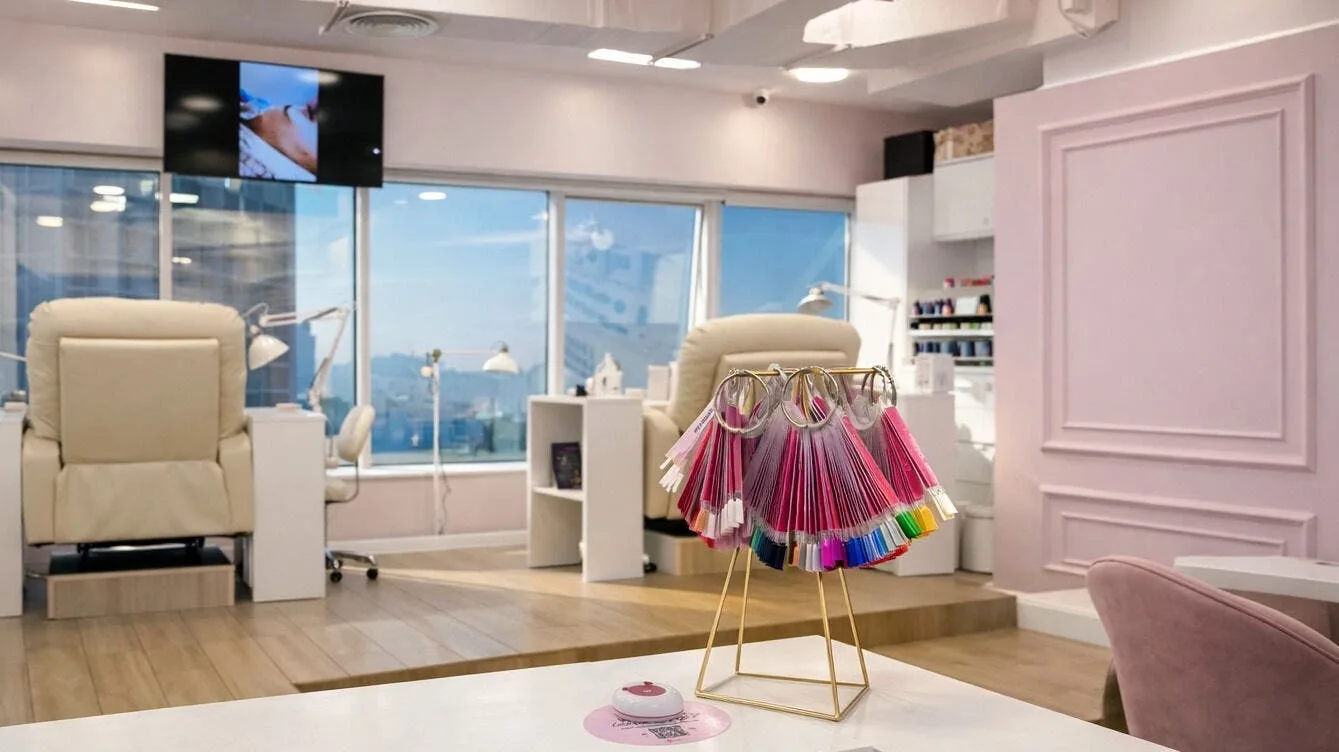 Modern salon interior with cream seating, city view windows, and colorful nail and lash sample display