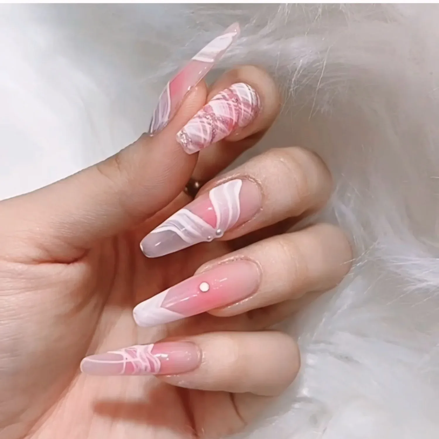 Manicured nails with pink and white geometric nail art designs and small jewel accents