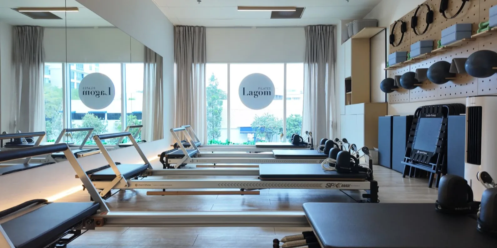 Spacious pilates studio with reformer machines, large windows, and organized equipment storage