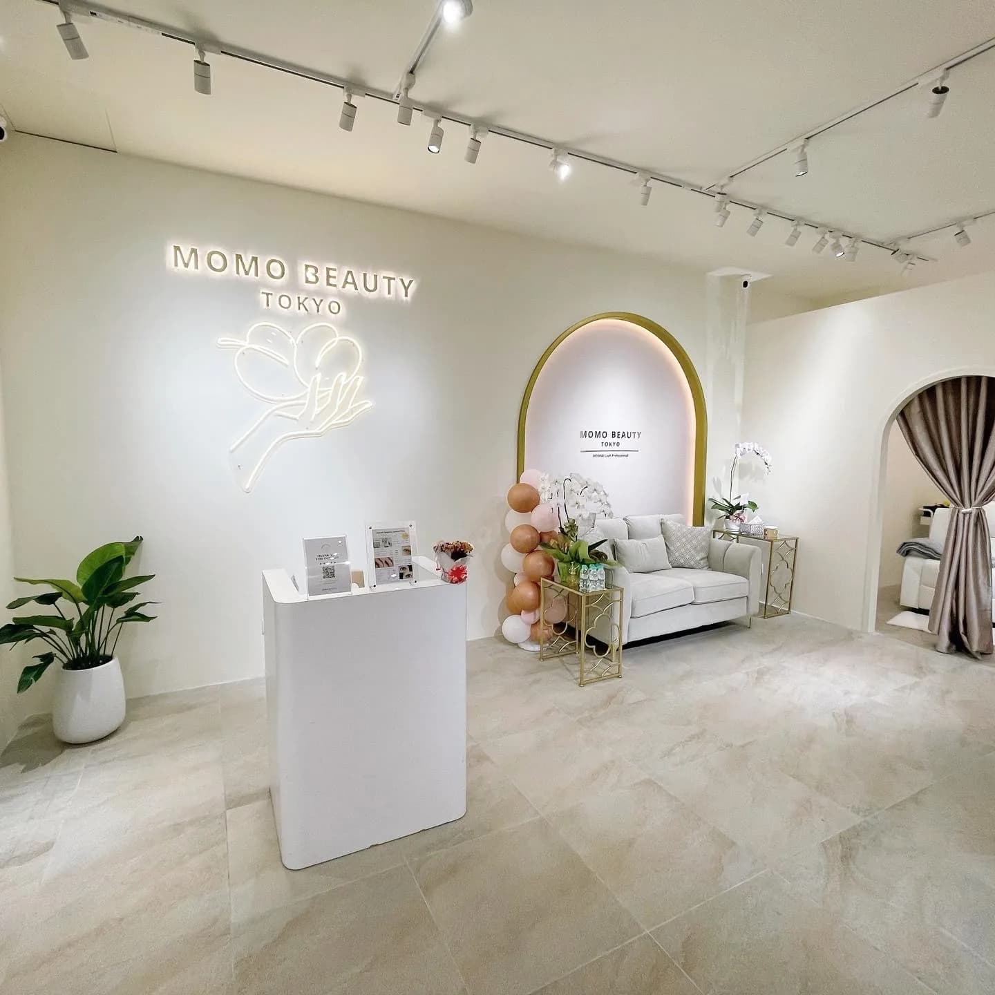 MOMO Beauty Tokyo salon interior with neon sign, white furniture, and modern decor