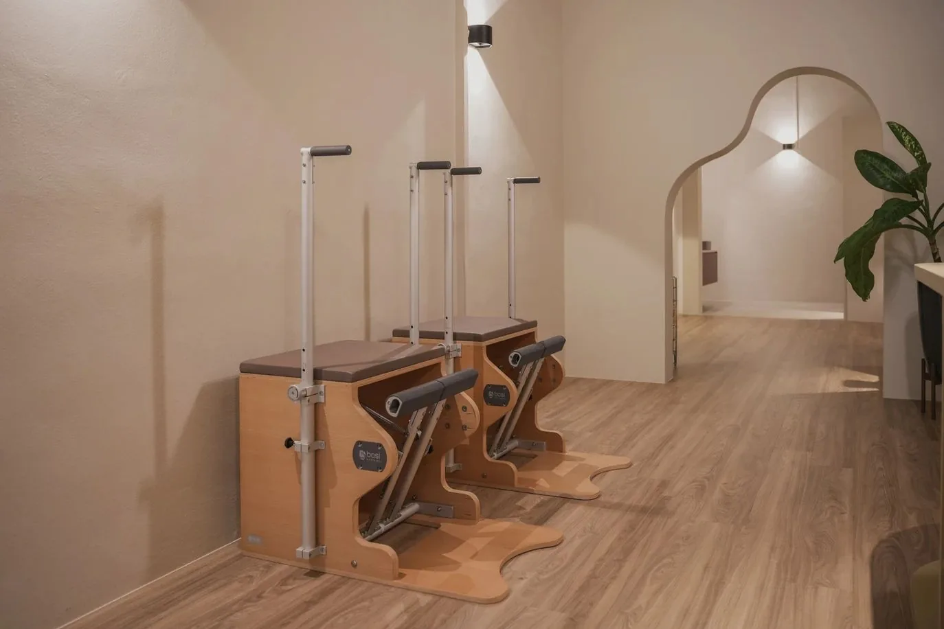 Pilates studio with three wooden reformer machines on wooden flooring and cream walls