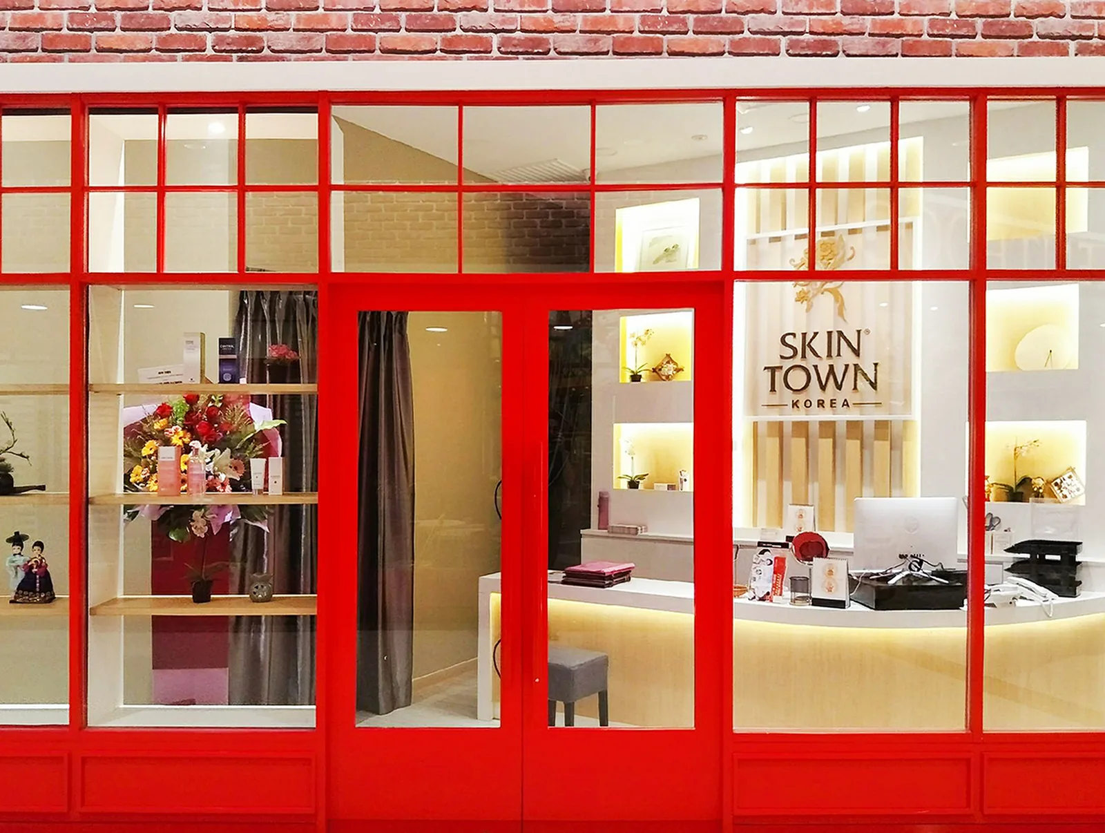 Red-framed storefront of Skin Town Korea beauty salon with illuminated interior and reception area