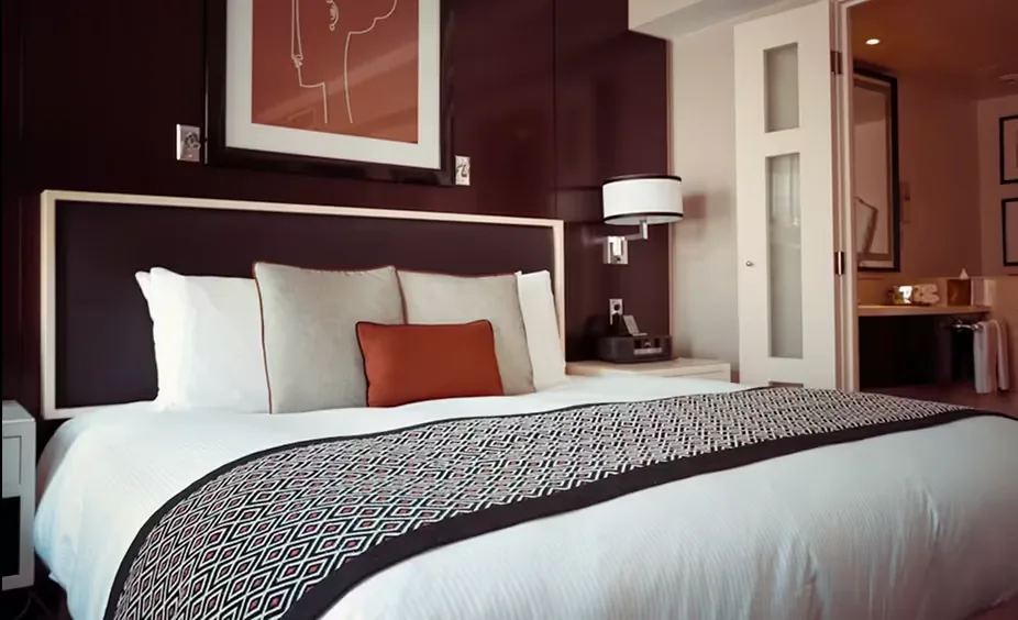 Modern bedroom with white bedding, patterned throw blanket, and burgundy accent walls.