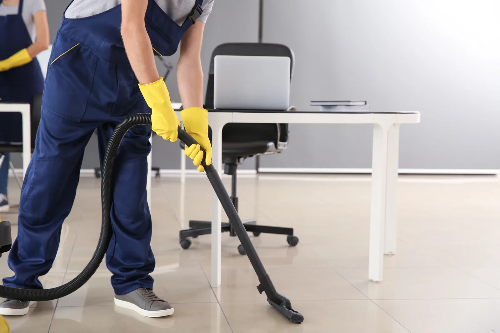 Cleaning worker vacuuming an office floor with professional equipment
