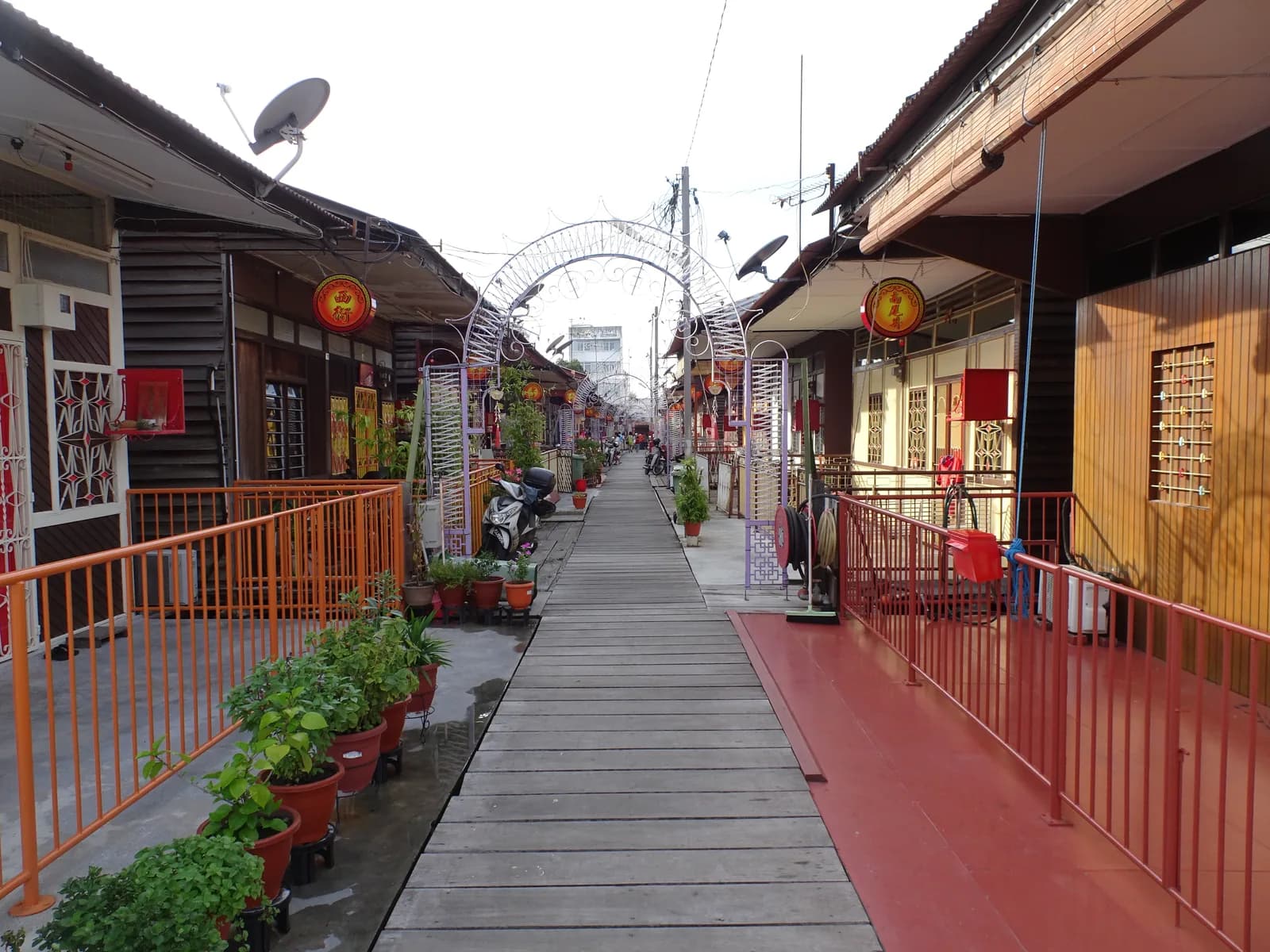 Covered wooden walkway through historic shophouses with red railings and traditional architecture
