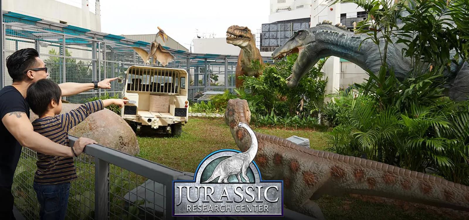 Dinosaur sculptures and exhibition area with visitors at an outdoor theme park attraction