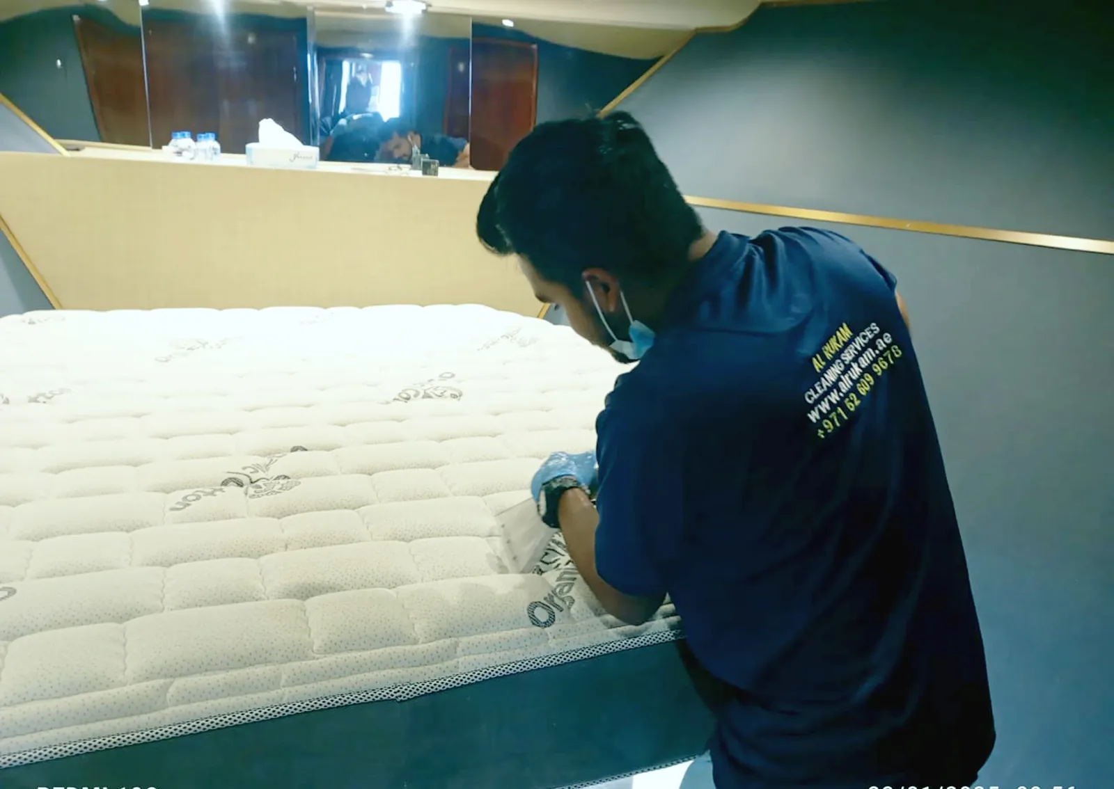 Staff member cleaning a white mattress with spray treatment