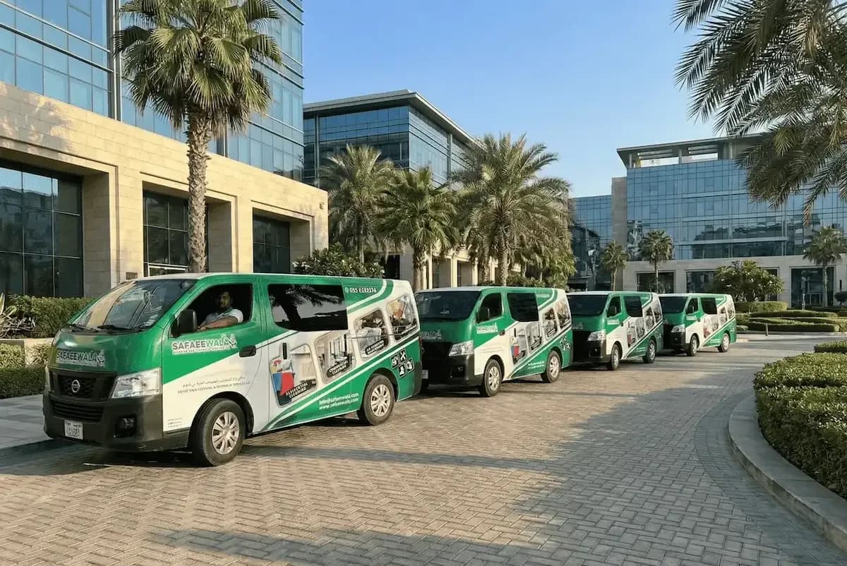 Fleet of five branded Safaeewala service vans parked in modern business district courtyard