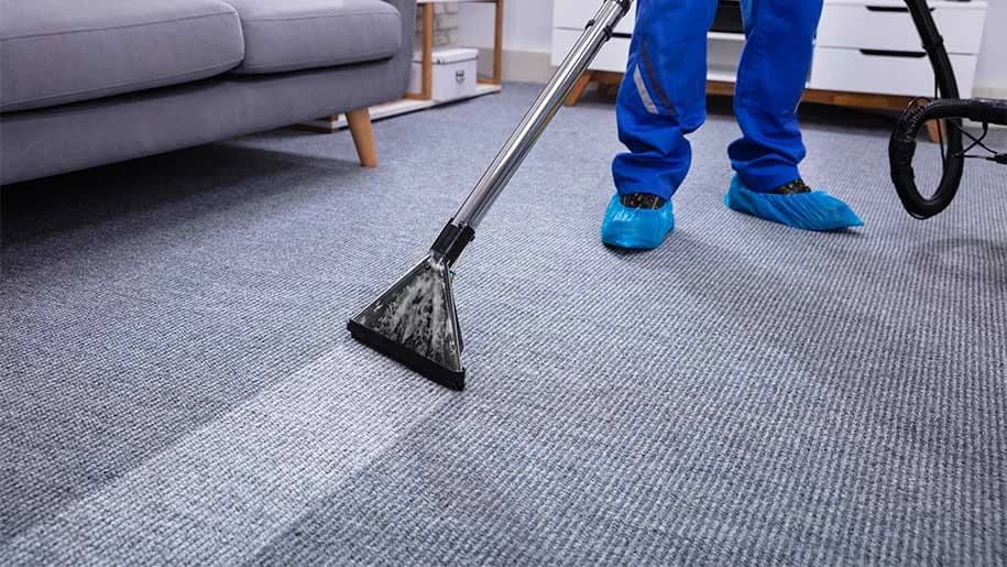 Worker using carpet cleaning equipment on carpeted floor in residential interior
