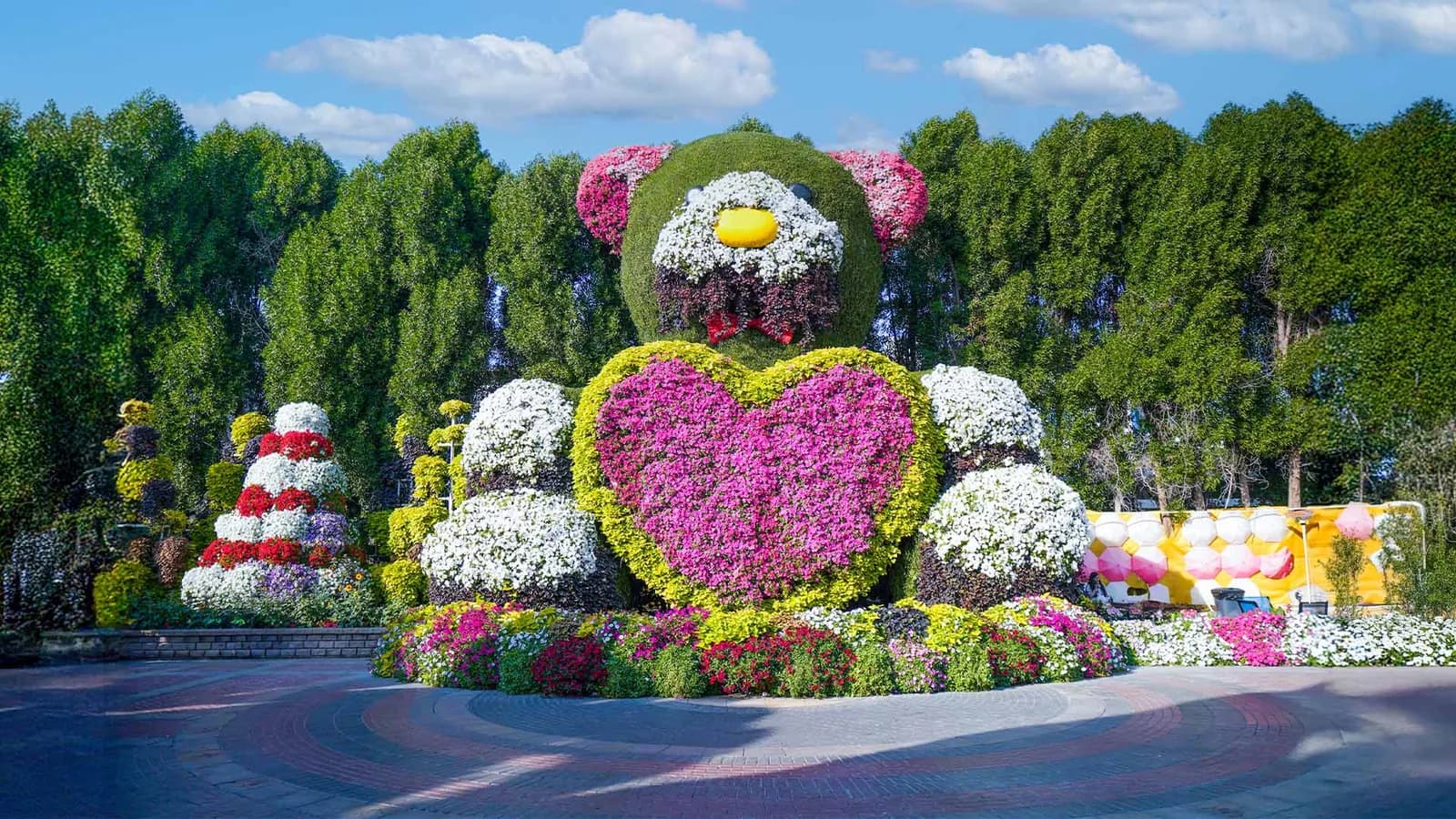Giant heart-shaped flower topiary with colorful blooms at Dubai Miracle Garden, surrounded by decorative hedges and landscaping